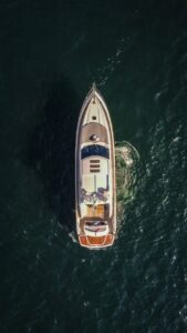 An aerial shot of a luxury yacht cruising through calm sea waters, showcasing opulence and adventure.