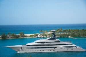 High-end yacht cruising along a tropical coastline with clear blue waters and lush greenery.