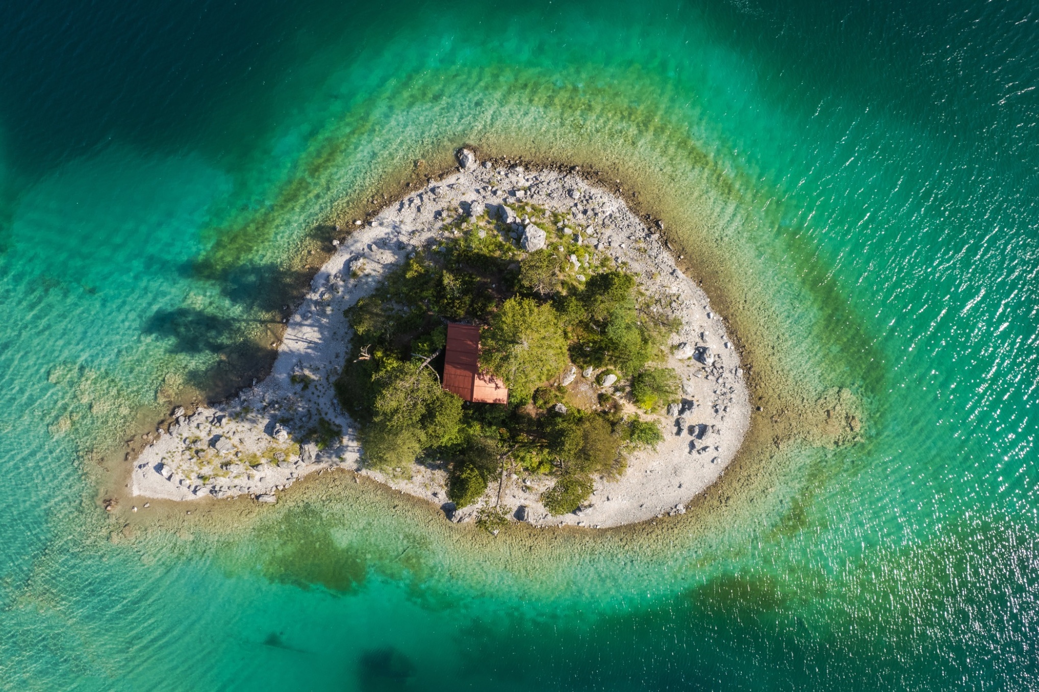 erial view of a small rocky island surrounded by crystal clear turquoise water in the Ionian Sea