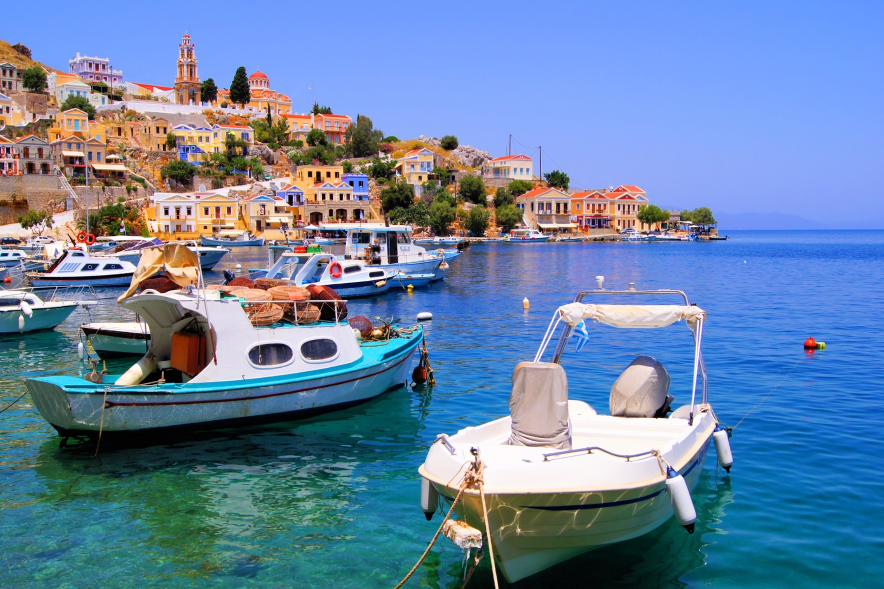 Symi’s postcard harbor — pastel mansions cascading down to crystal waters, where history meets haute living.