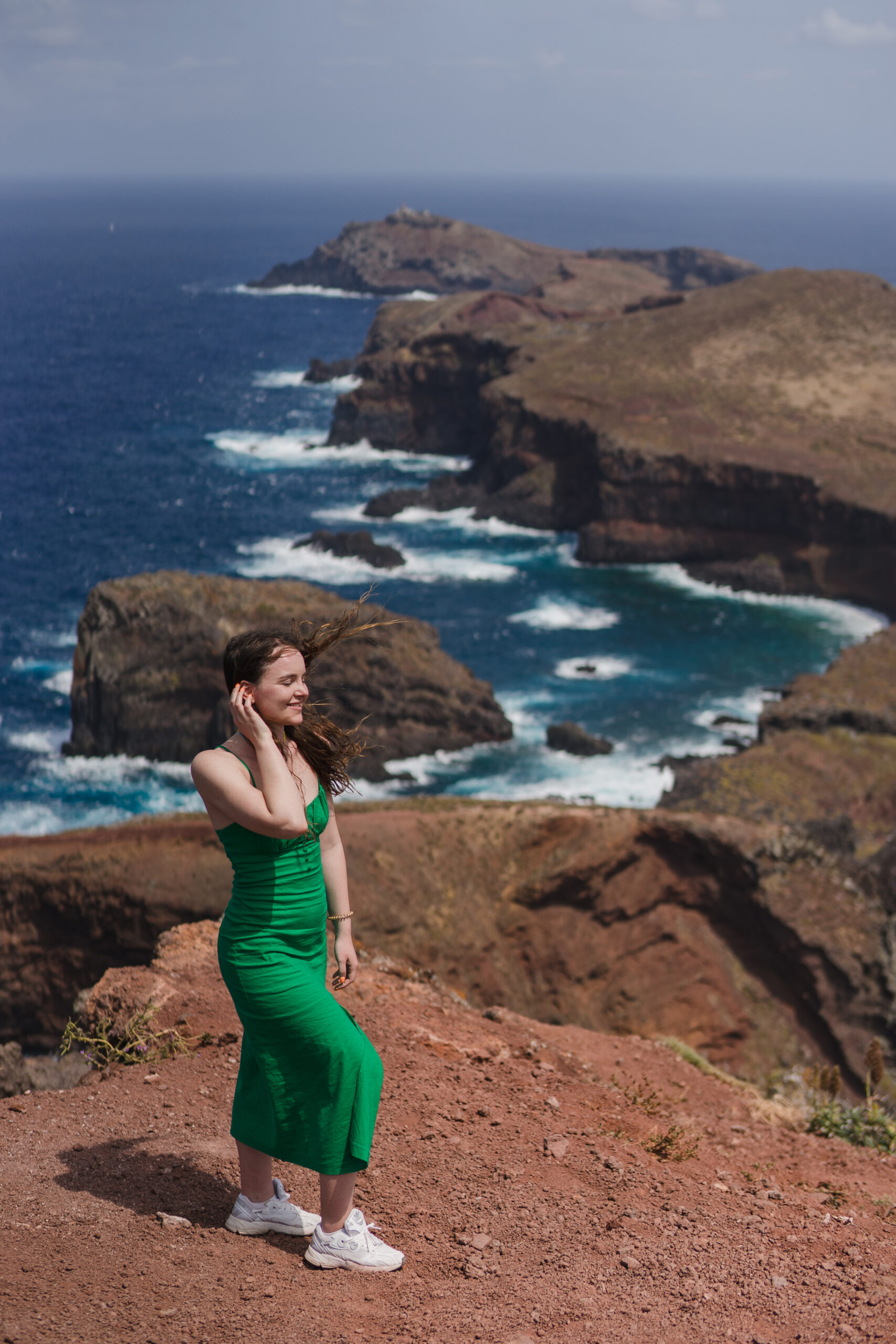 Young female tourist enjoying spectacular vie. Summer tourism by Atlantic ocean and mountains. Outdoor views on beautiful water, sky, cliffs, coastline and travel destination.