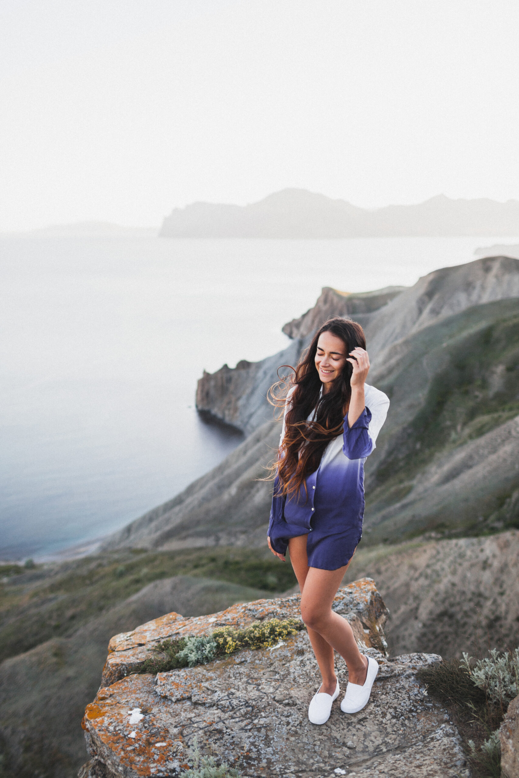 Woman standing on a cliff with a stunning view of sea coast with