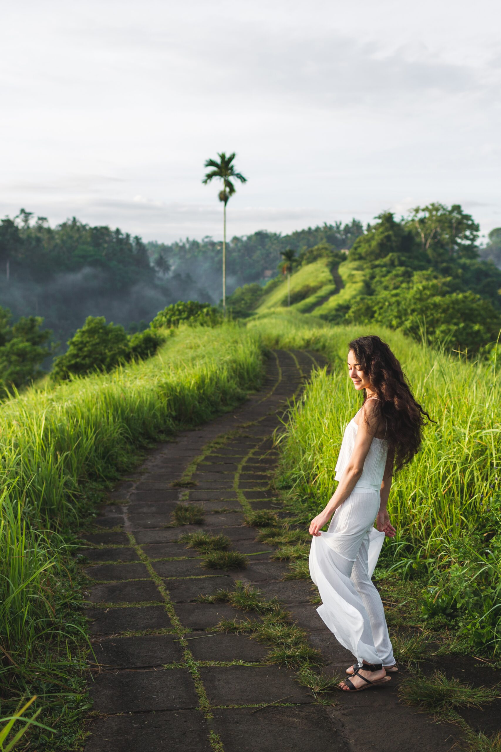 Young beautiful woman walking on Campuhan Ridge way of artists, in Bali, Ubud. Beautiful calm sunny morning