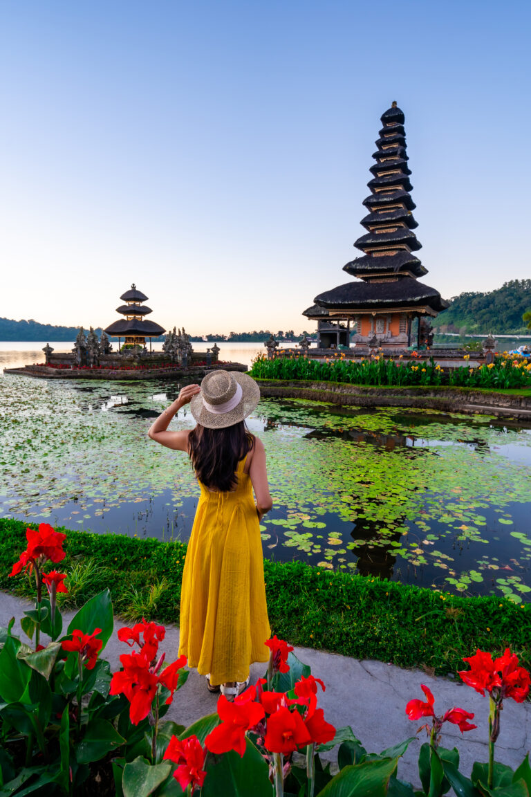 Young woman tourist relaxing and enjoying the beautiful view at Ulun Danu Beratan temple in Bali, Indonesia